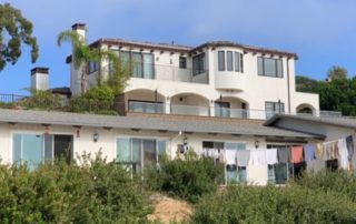 Dirty laundry hanging on clothes line in front of California mansion