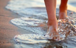 Woman easing heartbreak by walking through tidal surf on a beach